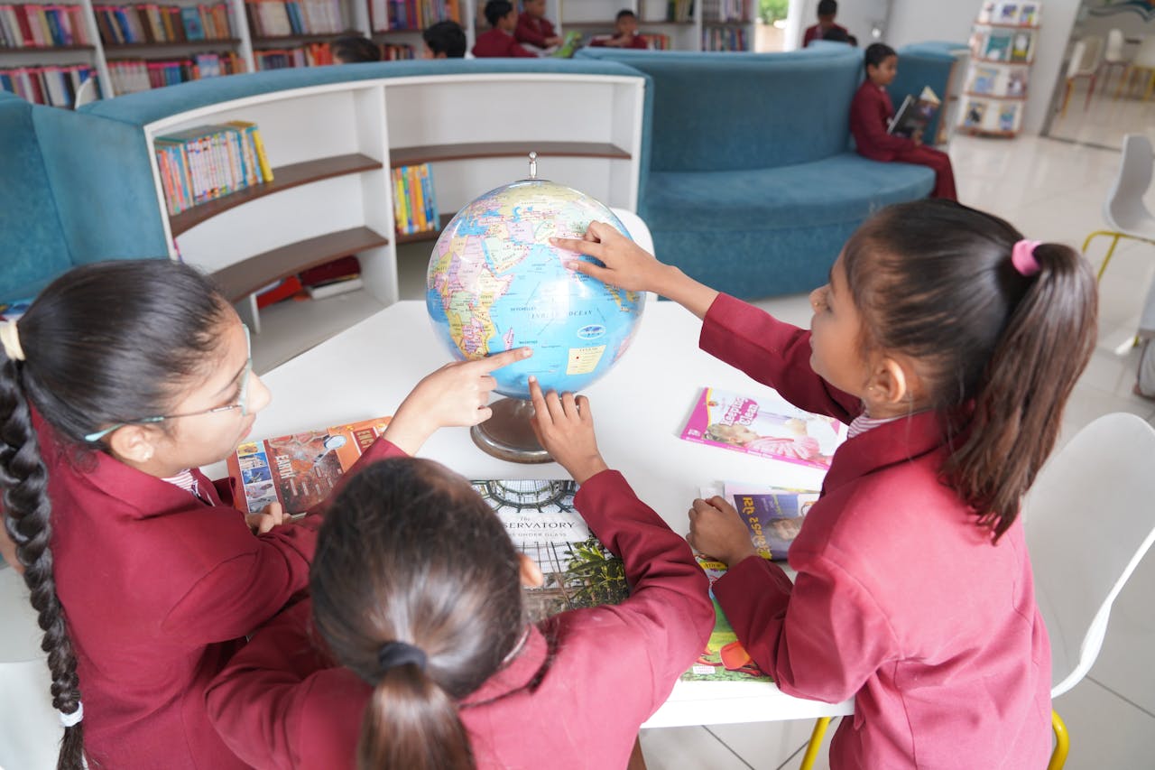 portfolio-04 Children in uniform learning geography with a globe in a contemporary library.