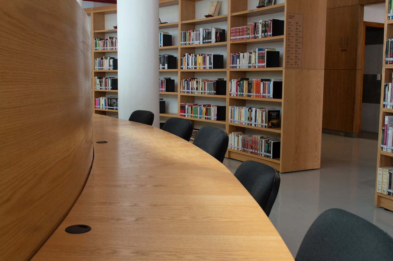 services-10 Spacious library interior featuring wooden bookshelves and a large conference table.